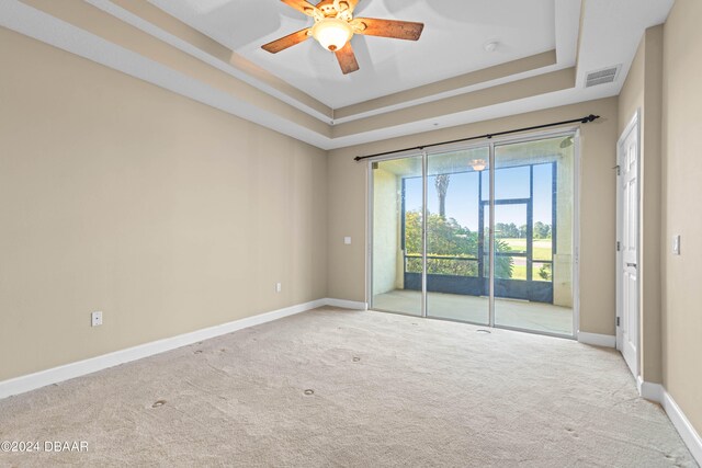 spare room with light colored carpet, ceiling fan, and a tray ceiling