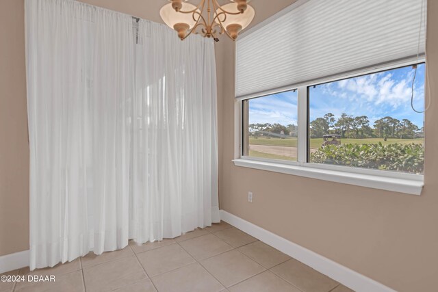 empty room featuring a chandelier and tile patterned flooring