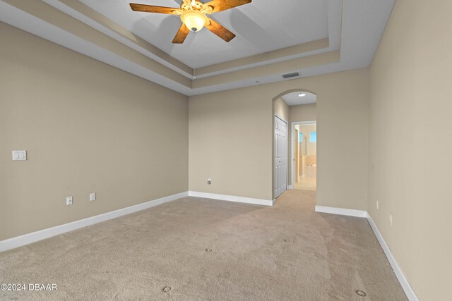 carpeted empty room featuring ceiling fan and a tray ceiling