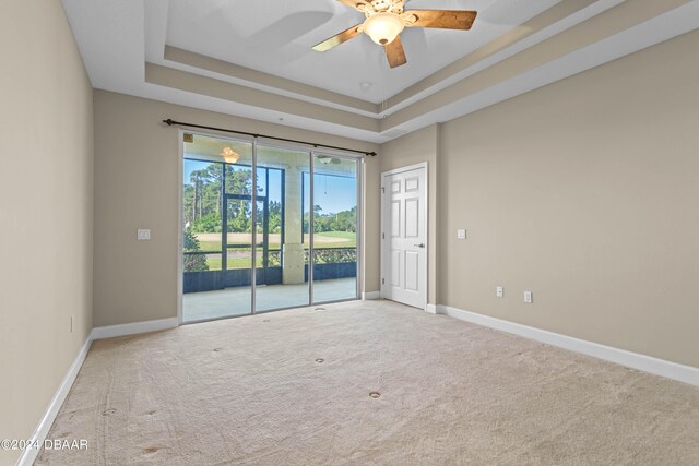 carpeted empty room with a tray ceiling and ceiling fan