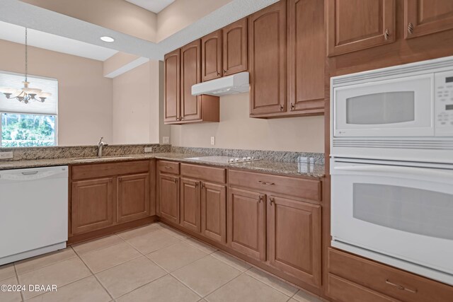 kitchen with light tile patterned flooring, decorative light fixtures, a notable chandelier, sink, and white appliances