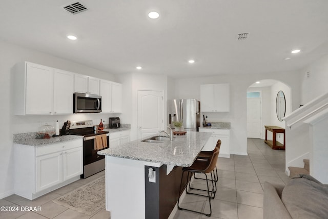 kitchen featuring a kitchen island with sink, stainless steel appliances, white cabinetry, and sink