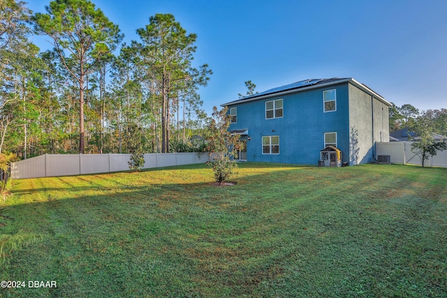 rear view of property with central air condition unit and a lawn