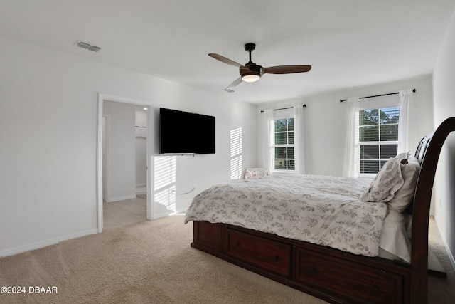 bedroom featuring ceiling fan, connected bathroom, and light colored carpet