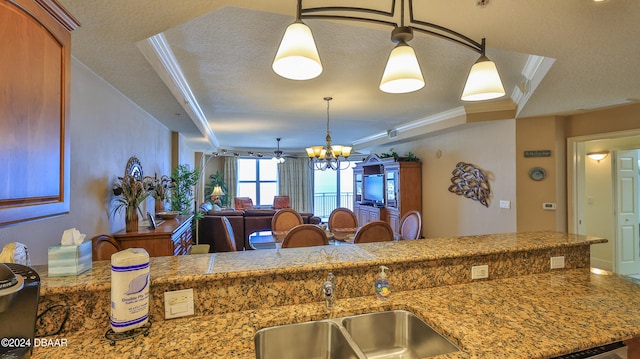 kitchen with hanging light fixtures, sink, ornamental molding, and a textured ceiling