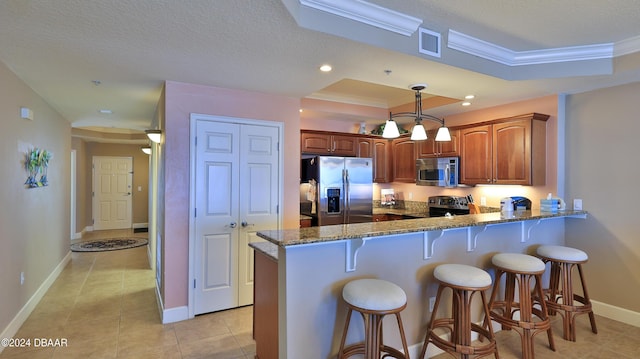 2403 S Atlantic Ave Unit 1210, Daytona Beach Shores, FL 32118 - kitchen with appliances with stainless steel finishes, crown molding, a peninsula, dark stone counters, and a breakfast bar