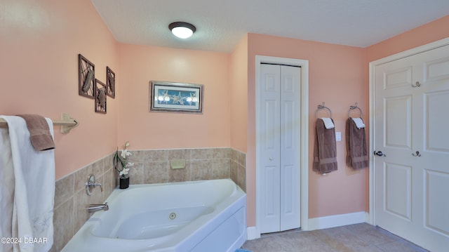 bathroom with a tub to relax in, a textured ceiling, and tile patterned floors