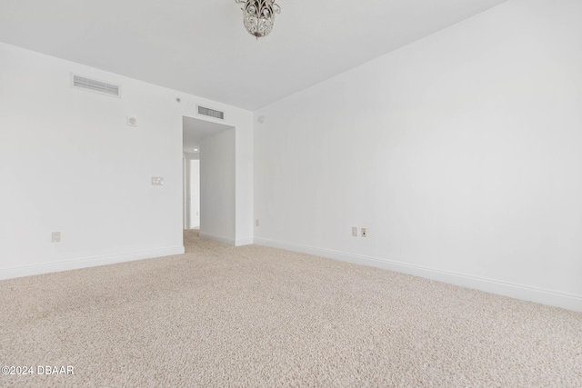231 Riverside Dr Unit 1209-1, Daytona Beach, FL 32117 - unfurnished room featuring light carpet, baseboards, and a chandelier