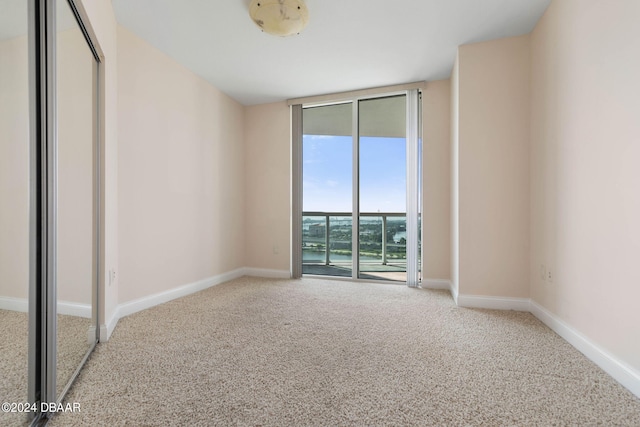231 Riverside Dr Unit 1209-1, Daytona Beach, FL 32117 - unfurnished bedroom featuring carpet floors, access to exterior, expansive windows, and baseboards