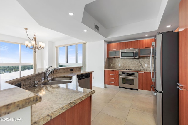 kitchen featuring backsplash, appliances with stainless steel finishes, hanging light fixtures, sink, and a chandelier