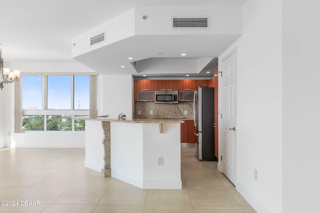 kitchen featuring appliances with stainless steel finishes, light stone countertops, light tile patterned floors, pendant lighting, and decorative backsplash