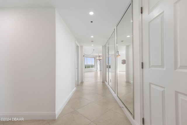 hallway with a notable chandelier and light tile patterned flooring