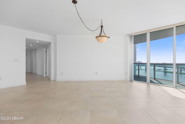 tiled spare room with a wall of windows and a water view