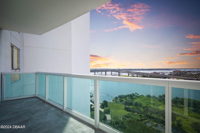 balcony at dusk featuring a water view