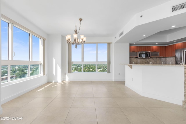 kitchen with a wealth of natural light, appliances with stainless steel finishes, and light stone counters