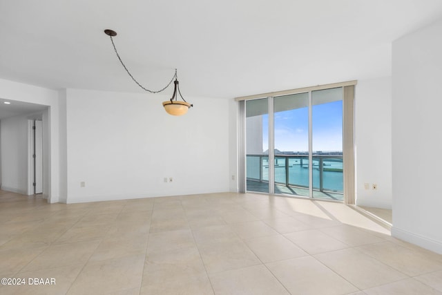 tiled empty room with a water view and floor to ceiling windows