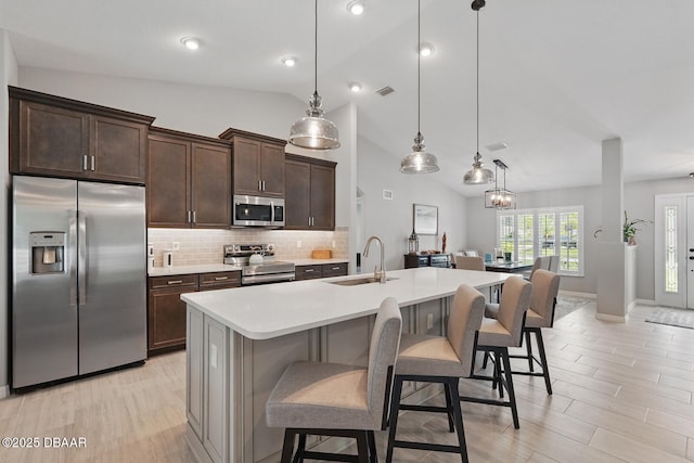 70 Esperanto Dr, Palm Coast, FL 32164 - kitchen featuring appliances with stainless steel finishes, vaulted ceiling, a kitchen bar, light countertops, and dark brown cabinets