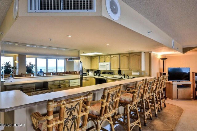 4601 S Atlantic Ave Unit 702, Ponce Inlet, FL 32127 - kitchen featuring light carpet, electric range oven, light countertops, a peninsula, and white microwave