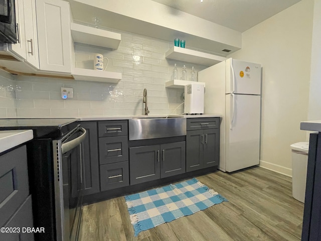 kitchen featuring light hardwood / wood-style floors, white cabinetry, sink, stainless steel range with electric cooktop, and white refrigerator