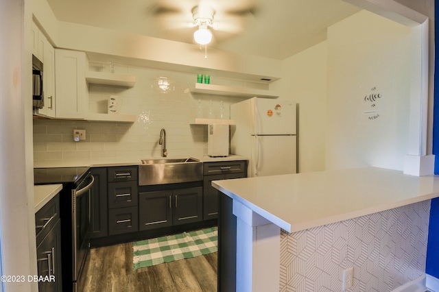 kitchen featuring sink, kitchen peninsula, appliances with stainless steel finishes, dark hardwood / wood-style floors, and white cabinets