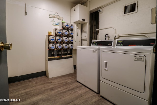 clothes washing area with wood-type flooring and washer and dryer