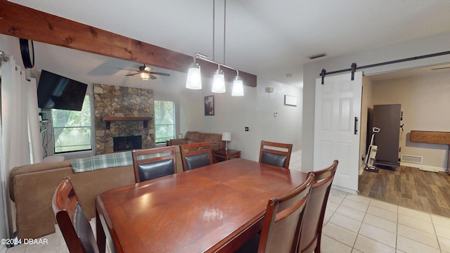 167 Fox Glen Ct, Ormond Beach, FL 32174 - dining room featuring a stone fireplace, a barn door, ceiling fan, beam ceiling, and light wood-type flooring