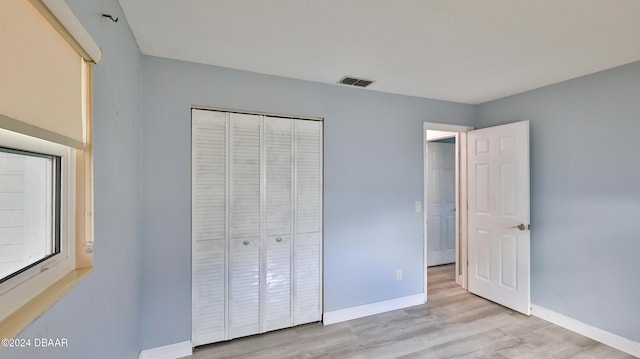 unfurnished bedroom with a closet and light hardwood / wood-style flooring