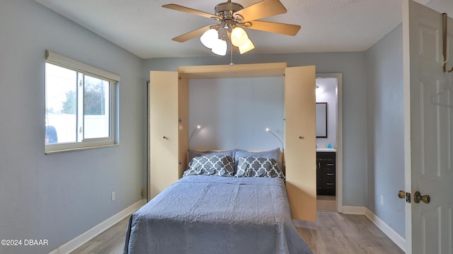 bedroom with a ceiling fan, connected bathroom, baseboards, and wood finished floors