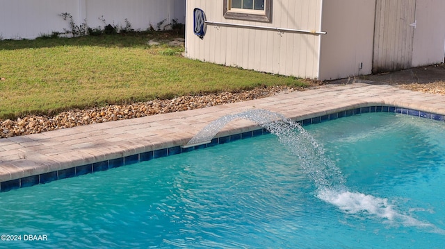 view of swimming pool with pool water feature, a shed, and a yard