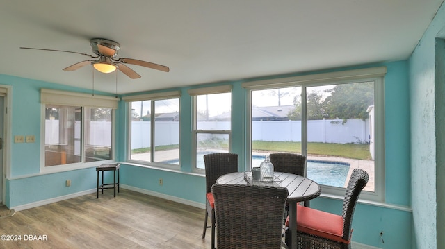 sunroom featuring ceiling fan and a water view