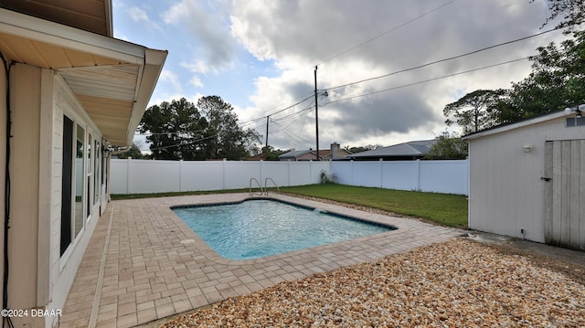 view of swimming pool featuring a lawn, a patio area, and a shed