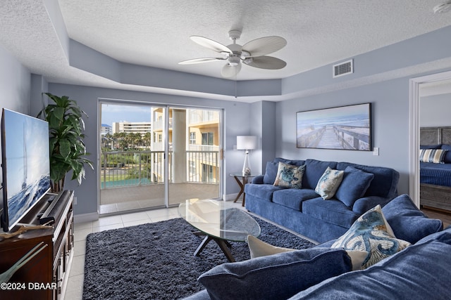 living room featuring a textured ceiling, ceiling fan, and light tile patterned flooring