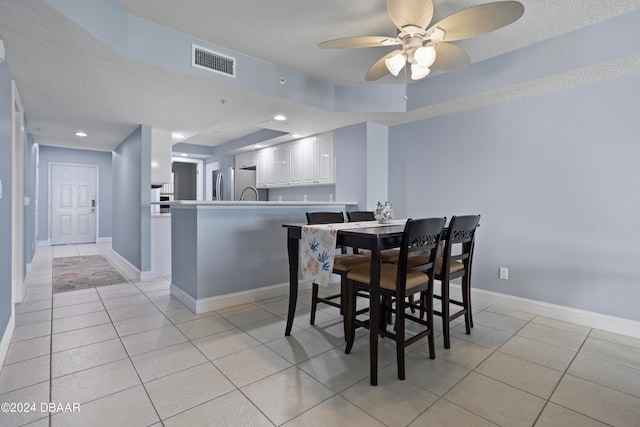 dining room with ceiling fan, light tile patterned floors, and a textured ceiling