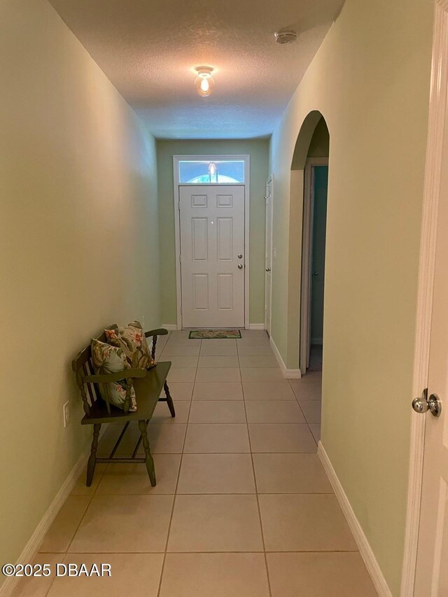119 Fishermans Cove Dr, Edgewater, FL 32141 - doorway to outside featuring a textured ceiling, light tile patterned floors, arched walkways, and baseboards