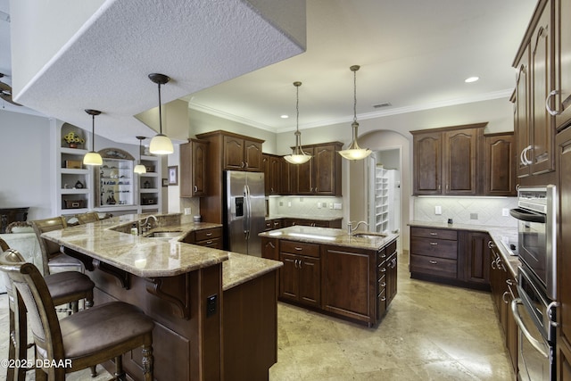 3 Indian Springs Dr, Ormond Beach, FL 32174 - kitchen featuring stainless steel appliances, an island with sink, a breakfast bar area, light stone countertops, and hanging light fixtures