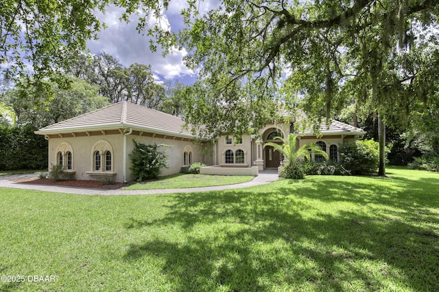3 Indian Springs Dr, Ormond Beach, FL 32174 - mediterranean / spanish house featuring stucco siding, a front lawn, a tiled roof, and view of wooded area