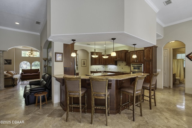 3 Indian Springs Dr, Ormond Beach, FL 32174 - kitchen featuring arched walkways, a kitchen breakfast bar, crown molding, a towering ceiling, and a peninsula