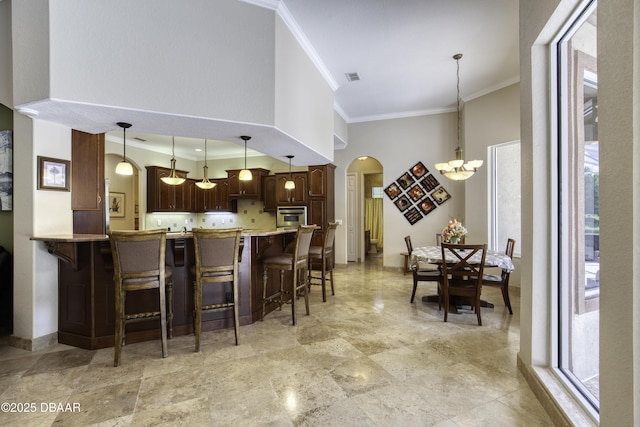 3 Indian Springs Dr, Ormond Beach, FL 32174 - kitchen featuring arched walkways, stainless steel oven, crown molding, a breakfast bar, and decorative backsplash