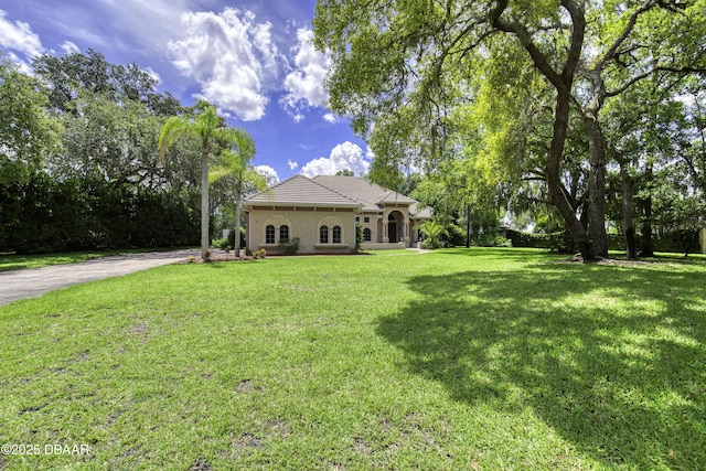 3 Indian Springs Dr, Ormond Beach, FL 32174 - view of side of home featuring a yard, stucco siding, driveway, and a tile roof