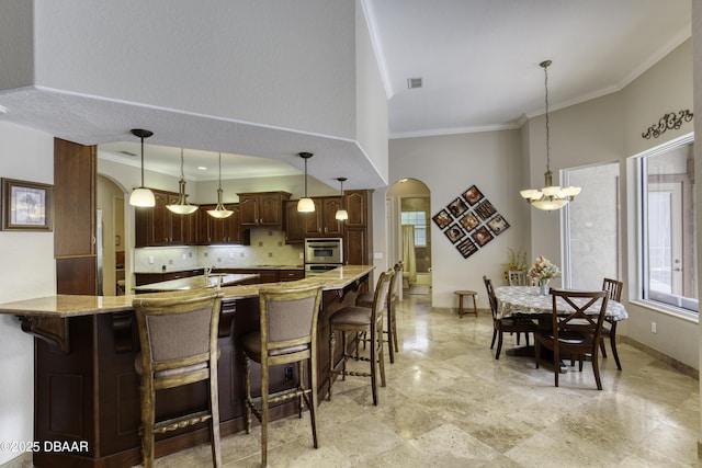 3 Indian Springs Dr, Ormond Beach, FL 32174 - kitchen with arched walkways, ornamental molding, backsplash, a chandelier, and a breakfast bar area