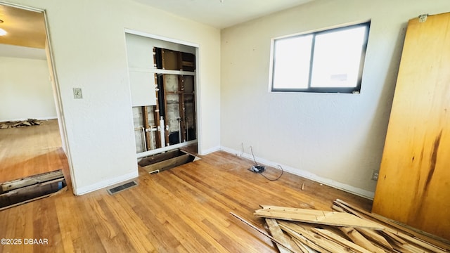 spare room featuring wood finished floors, visible vents, and baseboards