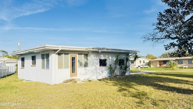 rear view of house featuring a yard and fence