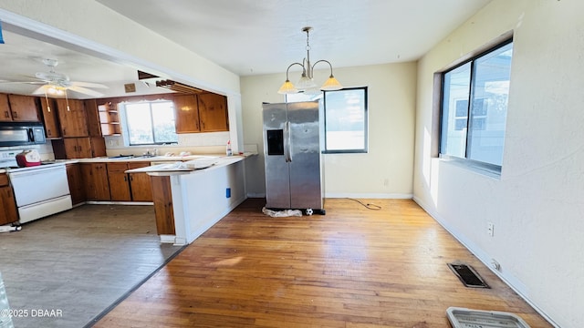 kitchen with white electric stove, black microwave, a peninsula, wood finished floors, and visible vents