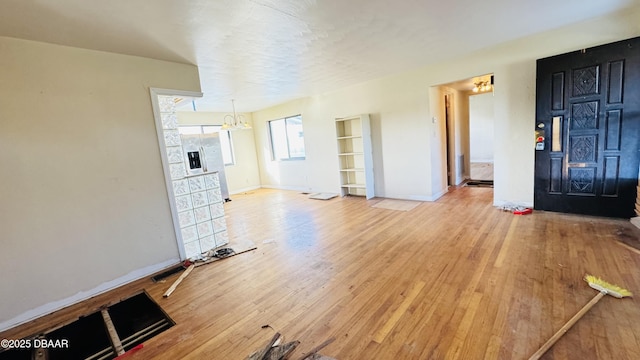 unfurnished living room featuring a notable chandelier, a fireplace, wood finished floors, and baseboards