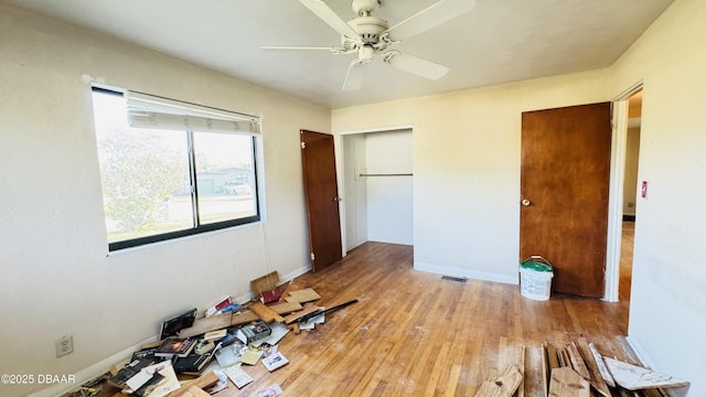 unfurnished bedroom with baseboards, visible vents, a ceiling fan, wood finished floors, and a closet