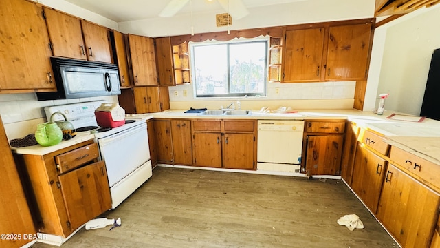 kitchen featuring white appliances, brown cabinets, a sink, and wood finished floors