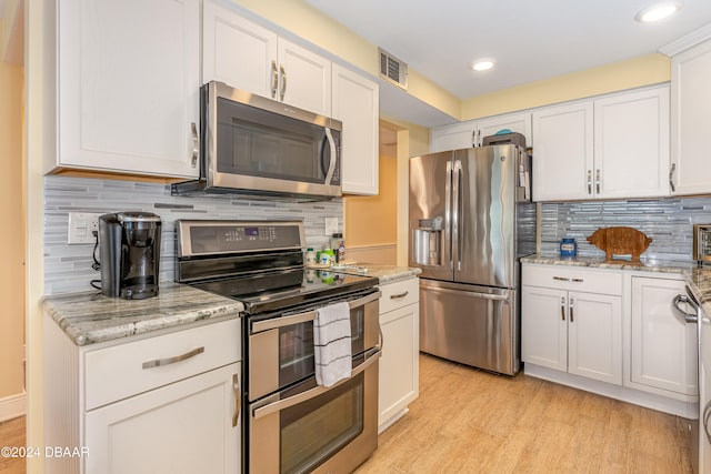 kitchen featuring white cabinets, decorative backsplash, light hardwood / wood-style flooring, light stone countertops, and appliances with stainless steel finishes