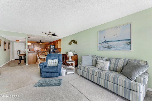 living room featuring a textured ceiling, light colored carpet, and ceiling fan