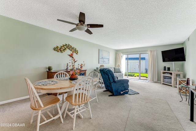 dining area featuring a textured ceiling, light colored carpet, and ceiling fan