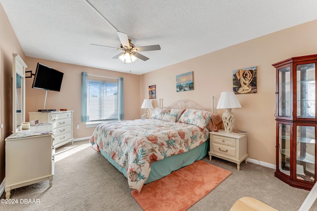 bedroom with a textured ceiling, light colored carpet, and ceiling fan